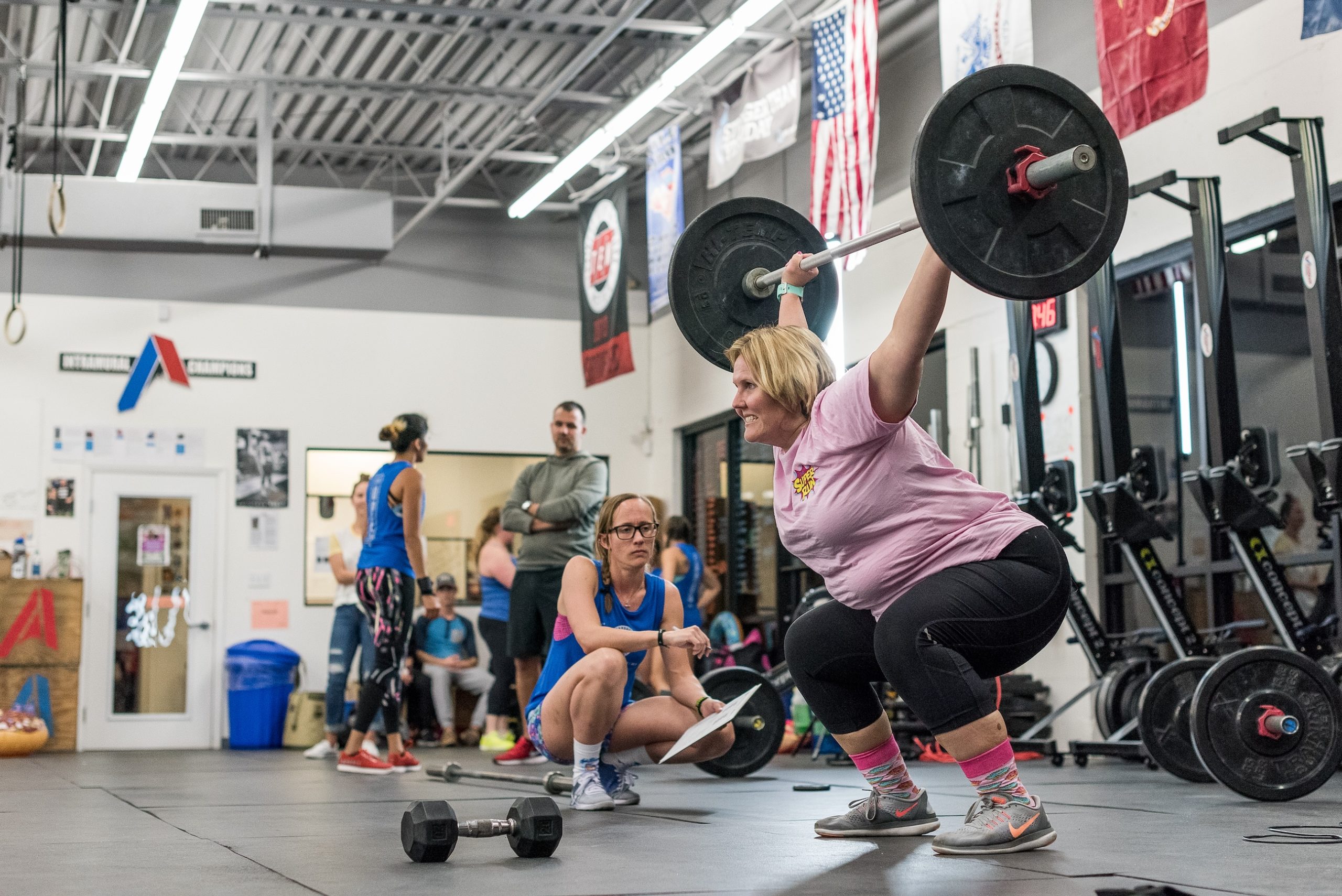 Middle-aged woman performs overhead squats during a CrossFit Open workout. 