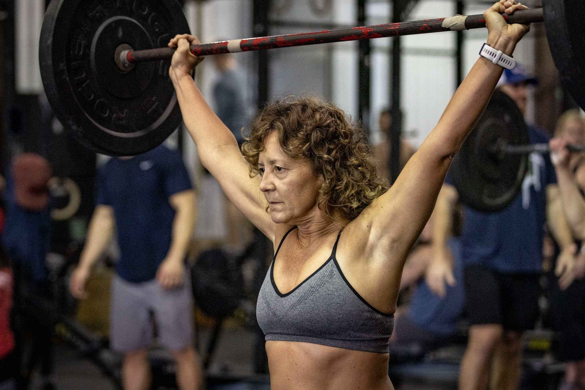 Theresa Sbarra holds a barbell overhead.