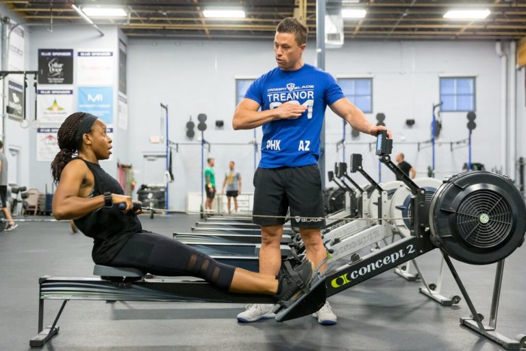 Coach talking to an athlete who is on the rower